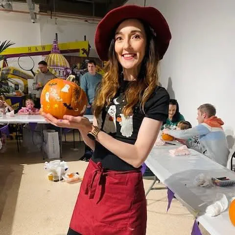 Halloween workshop leader holding a decorated pumpkin